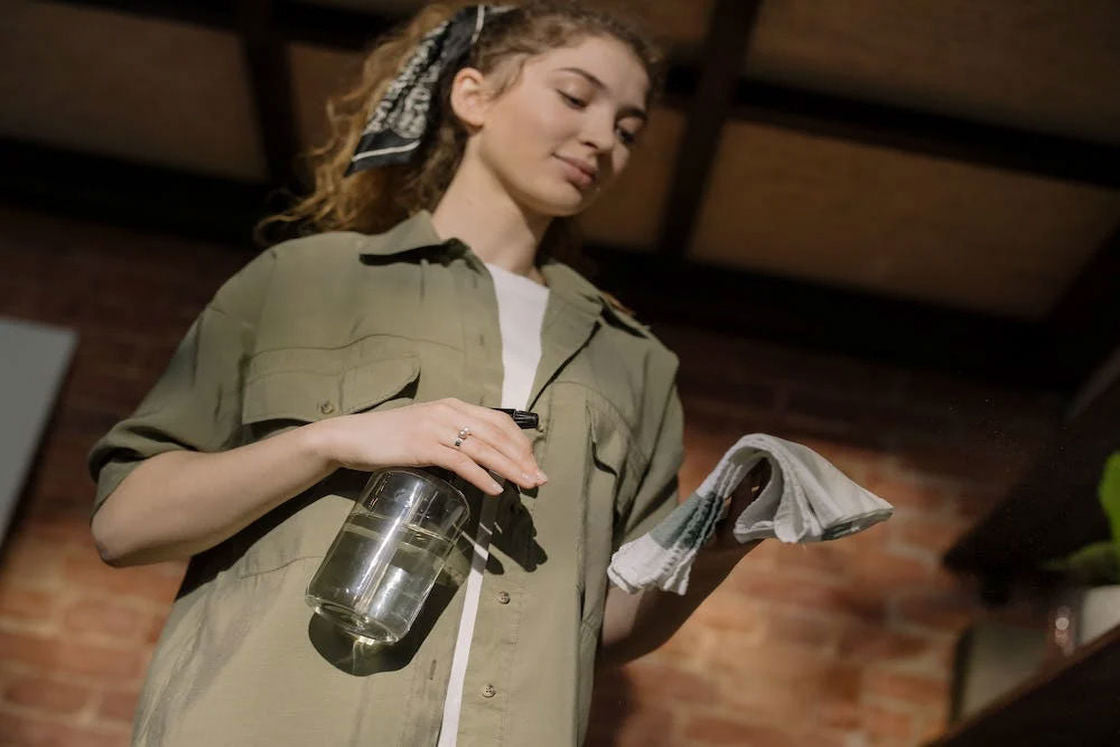 Woman holding a gray spray bottle and white rag