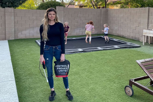 Woman holding a bag of Self Control pesticide mixture while her kids are playing in the background