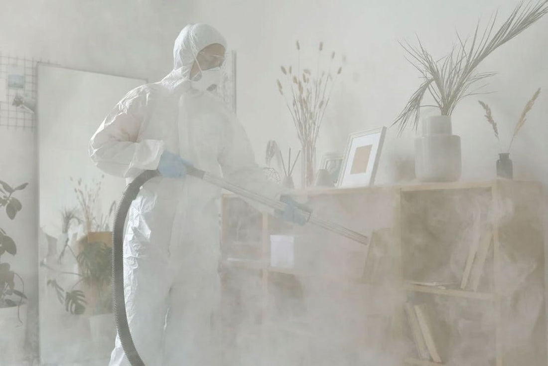 Man wearing a white protective gear while spraying pest control chemicals to a room