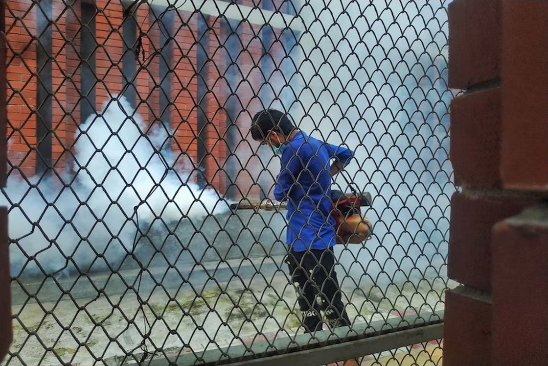 Man spraying pest control chemicals on a building's façade